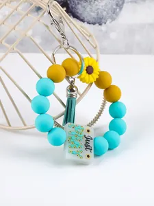 Detailed view of teal and yellow silicone bead keychain with sunflower and tassel