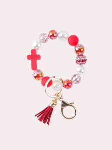 Detailed view of silicone beaded bracelet keychain with red tassel and engraved cross