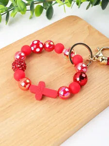 Detailed view of red silicone beaded keychain featuring an engraved cross and tassel