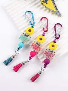Close-up of silicone bead keychains featuring daisy charms and 'Just PRAY' acrylic blocks.