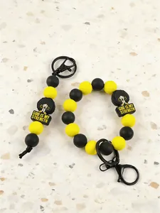 Detail view of yellow and black silicone bead keychain with 'God is my strength' charm