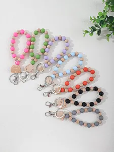 Detail view of colorful silicone and wooden beaded wristlet keychains with engraved charms