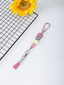 Detalle de llavero rosa con cuentas de margarita, amuleto de silicona y borla de PU
