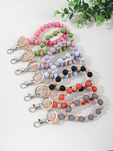 Variety of silicone and wood beaded keychain wristlets with engraved wooden charms.