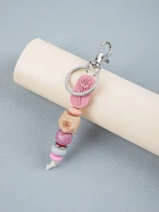 Close-up of silicone keychain with rose embossed charm and wooden butterfly bead.