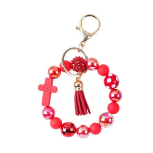 Vibrant red silicone bead bracelet keychain featuring a cross charm and tassel decoration