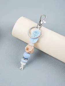 Detailed view of light blue silicone rose charm and engraved wooden bead keychain charm