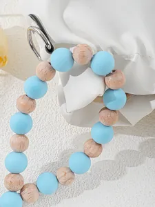 Close-up of light blue silicone and natural wooden beads for keychain or phone strap.
