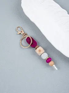 Detailed view of rose and butterfly engraved silicone and wooden bead keychain pendant