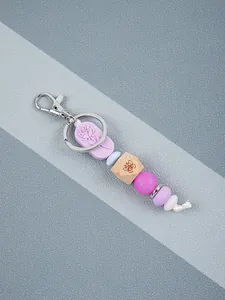 Detailed view of handmade silicone and wooden bead keychain with rose pattern engraving