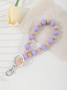 Detail of purple silicone and wooden bead keychain wristlet with a cute laser engraving.