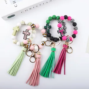 Multi-color silicone bead keychains with cross charms and long tassels shown on white