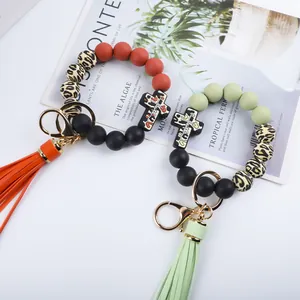 Detailed view of silicone beaded wristlet keychain featuring cross charm and long tassel