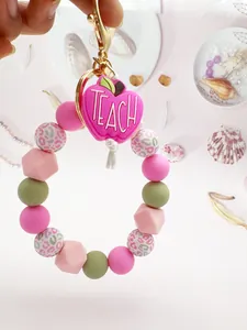 Detail of silicone beaded keychain with pink "TEACH" apple charm for teacher appreciation.
