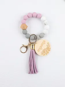 Close-up of a silicone bead wristlet keychain with purple tassel and mama engraved wood tag