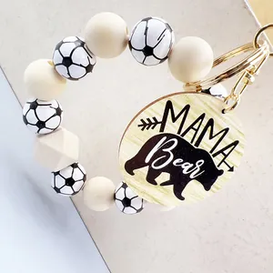 Detalle de llavero de cuentas de madera con motivo de fútbol y etiqueta Mama Bear.