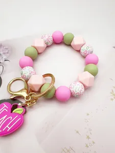 Detailed macro view of a colorful silicone bead keychain with a pink Teach apple charm
