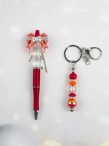 Close-up of a stylish red bow beaded pen and matching crystal bead keychain set for DIY gifts