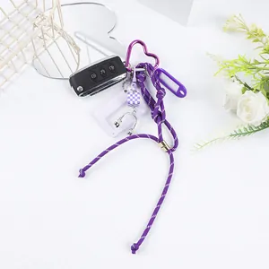 Close-up detail of purple paracord keychain featuring a heart carabiner and mini headphone charm