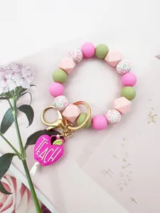 Close-up detail of silicone beaded wristlet keychain with pink TEACH heart charm