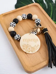 Close-up of silicone bead keychain with engraved 'mama' wood tag and tassel.