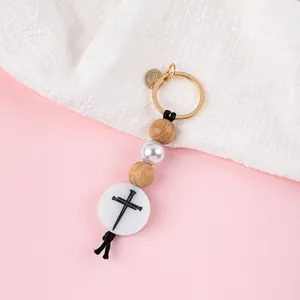 Portachiavi a croce fatto a mano con perle in legno e ciondolo per borsa bianco lucido.