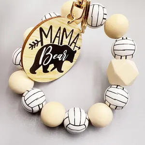 Detalle de una placa de madera grabada Mama Bear en un llavero de cuentas de voleibol