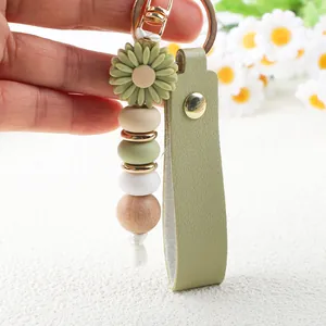 Detailaufnahme eines Gänseblümchen-Schlüsselanhängers mit Silikonperlen und Lederband.
