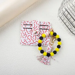Macro detail view of baseball patterned card holder with yellow and black beaded keychain.