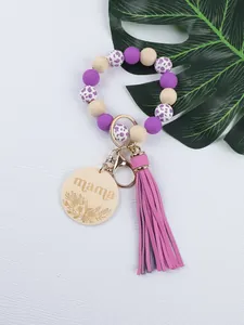 Close-up of silicone bead keychain with engraved mama wooden disc and purple tassel