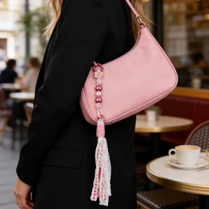 Close-up of handmade beaded tassel bag charm featuring lace and pink fabric strips