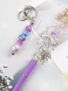 Detailed view of handmade purple beaded pen with rhinestone bow and crystal keychain