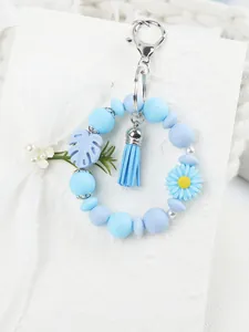 Blaues Silikon-Schlüsselanhänger-Armband mit Gänseblümchen und passendem Quastenanhänger.