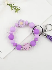 Nahaufnahme eines lila Silikonperlen-Armband-Schlüsselanhängers mit Gänseblümchen