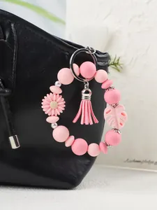 Detailansicht eines rosa Silikon-Schlüsselanhängers mit Gänseblümchen an einer Tasche.