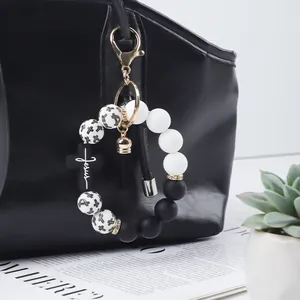 Detail view of a silicone cross beaded keychain bracelet with black tassel on bag