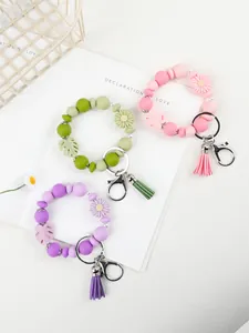 Drei bunte Silikonperlen-Armband-Schlüsselanhänger mit Gänseblümchen und Quaste im Detail.
