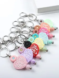 Close-up of colorful heart-shaped silicone keychains with Nurse Life engraving and daisy charms.