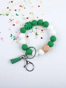 Detailed view of green and white silicone beaded keychain with tassel and leaf charm