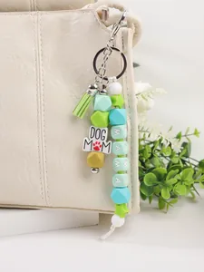 Detail van kralensleutelhanger met de DOG MOM en MAMA bedeltjes aan een witte tas