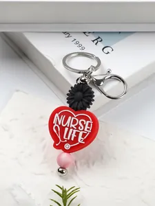 Close-up of a Nurse Life silicone heart keychain with black daisy and pink bead charm
