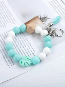 Detail shot of mint green and white silicone beaded keychain with leaf charm and tassel
