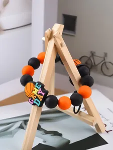 Primer plano de pulsera de cuentas de silicona con tema de baloncesto y dije GAME DAY en soporte.