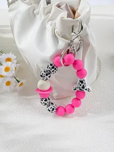 Nahaufnahme des rosa Silikon-Schlüsselanhängers mit Kuhmuster an einer weißen Tasche