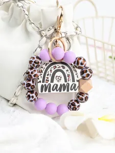 Close-up of a leopard print and purple bead mama keychain on a white bag