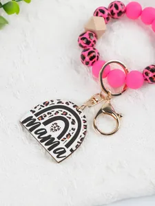 Close-up of pink leopard print beaded wristlet keychain with a "mama" rainbow acrylic charm.