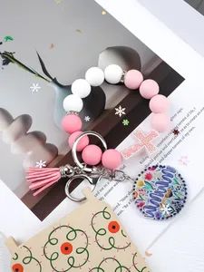 Detailed view of silicone bead wristlet keychain with Mama charm and pink tassel