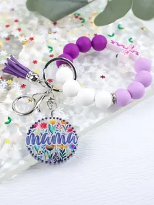 Detail of silicone bead keychain wristlet featuring purple tassel and floral mama charm