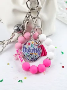 Detail of the silicone bead mama bracelet keychain with pink tassel and floral cross.