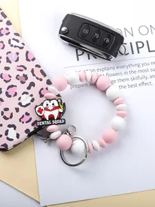 Close-up detail of cute pink and white silicone bead keychain with dental squad charm